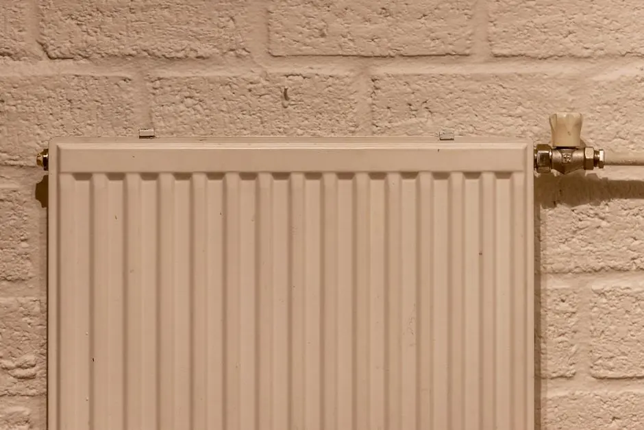 A clean white radiator mounted on a textured brick wall, indoors and well-lit.