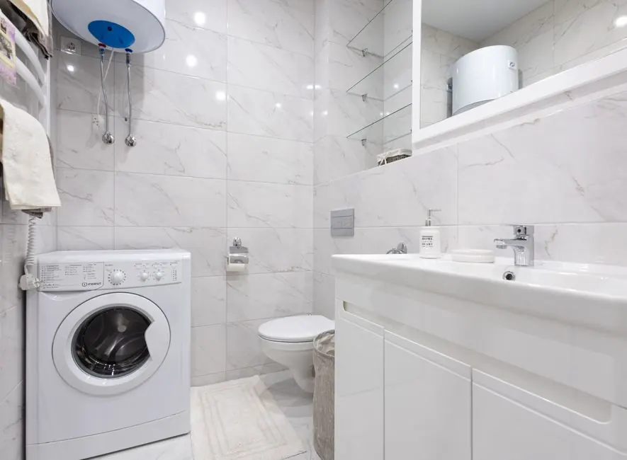 Bright minimalist bathroom featuring a washing machine and modern fixtures.